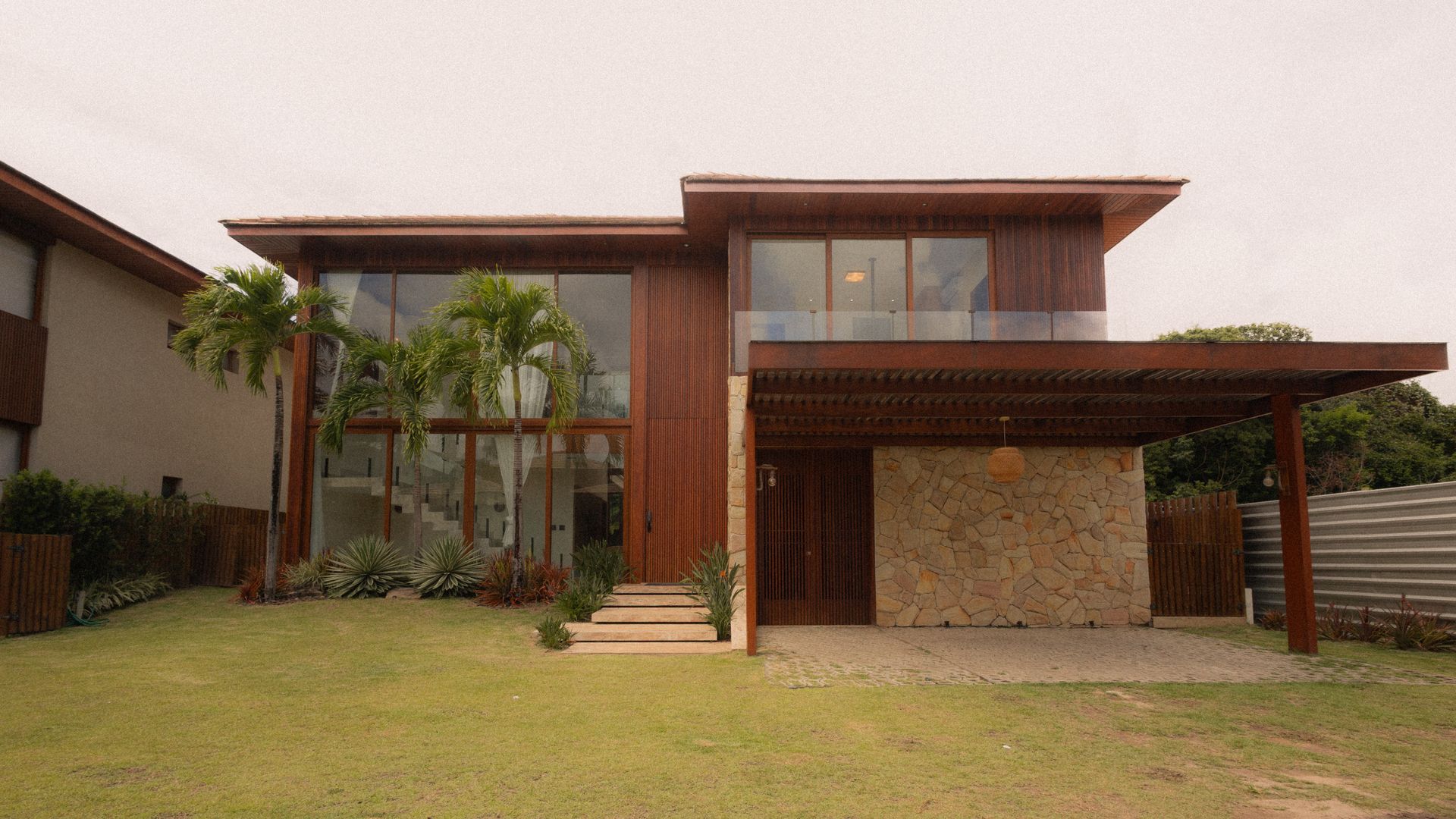 Casa moderna de madeira e pedra com jardim e palmeiras em condomínio no interior de Minas